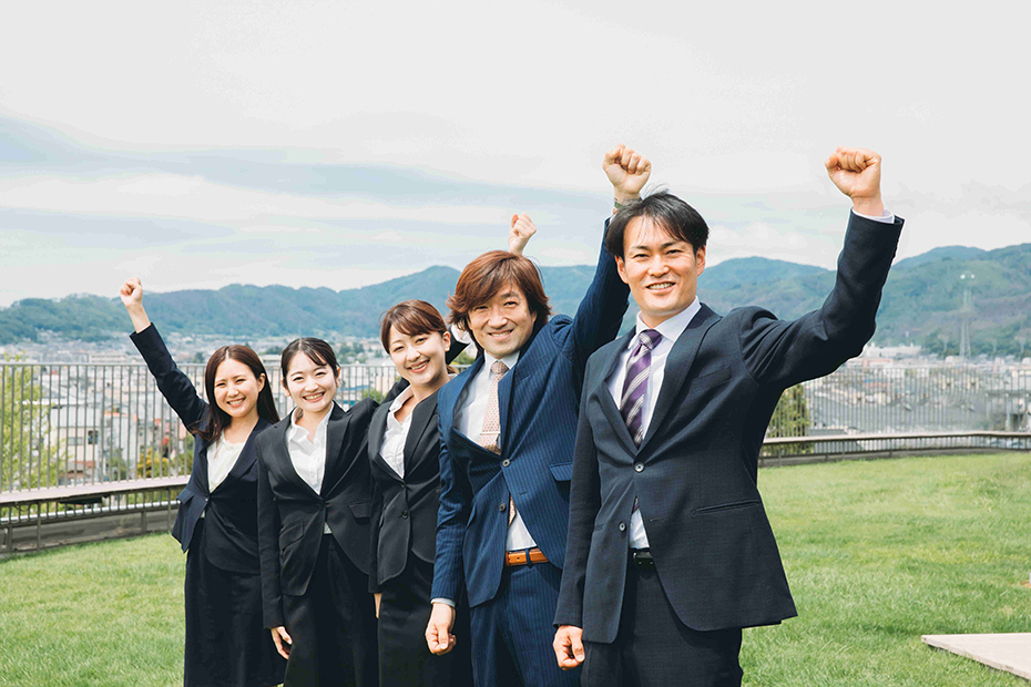 スーツ姿の男女が笑顔でガッツポーズをしている写真