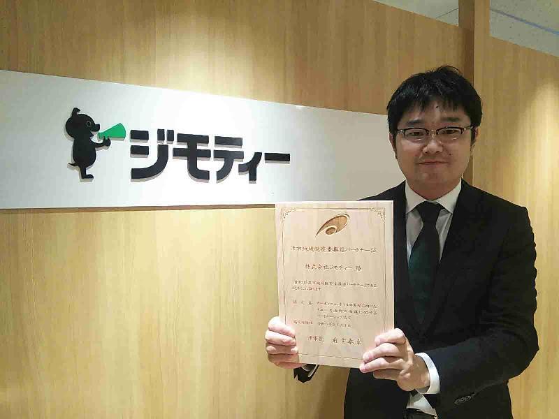 写真：パートナー証を持つジモティー担当者