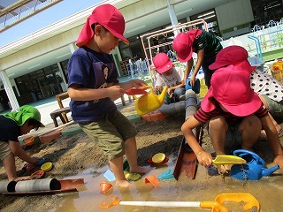 写真：砂遊び場で水を使って遊ぶ子どもたち