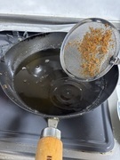 写真:油の中の異物を網で取り除く