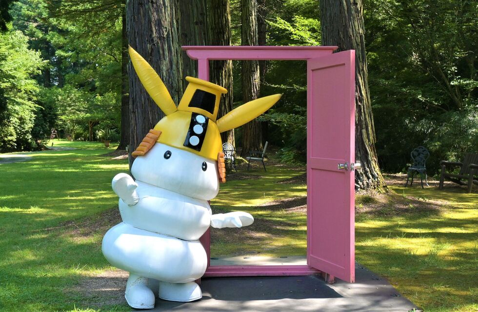 シロモチくんがピンクのドアの前でこちらに向かって立っている様子